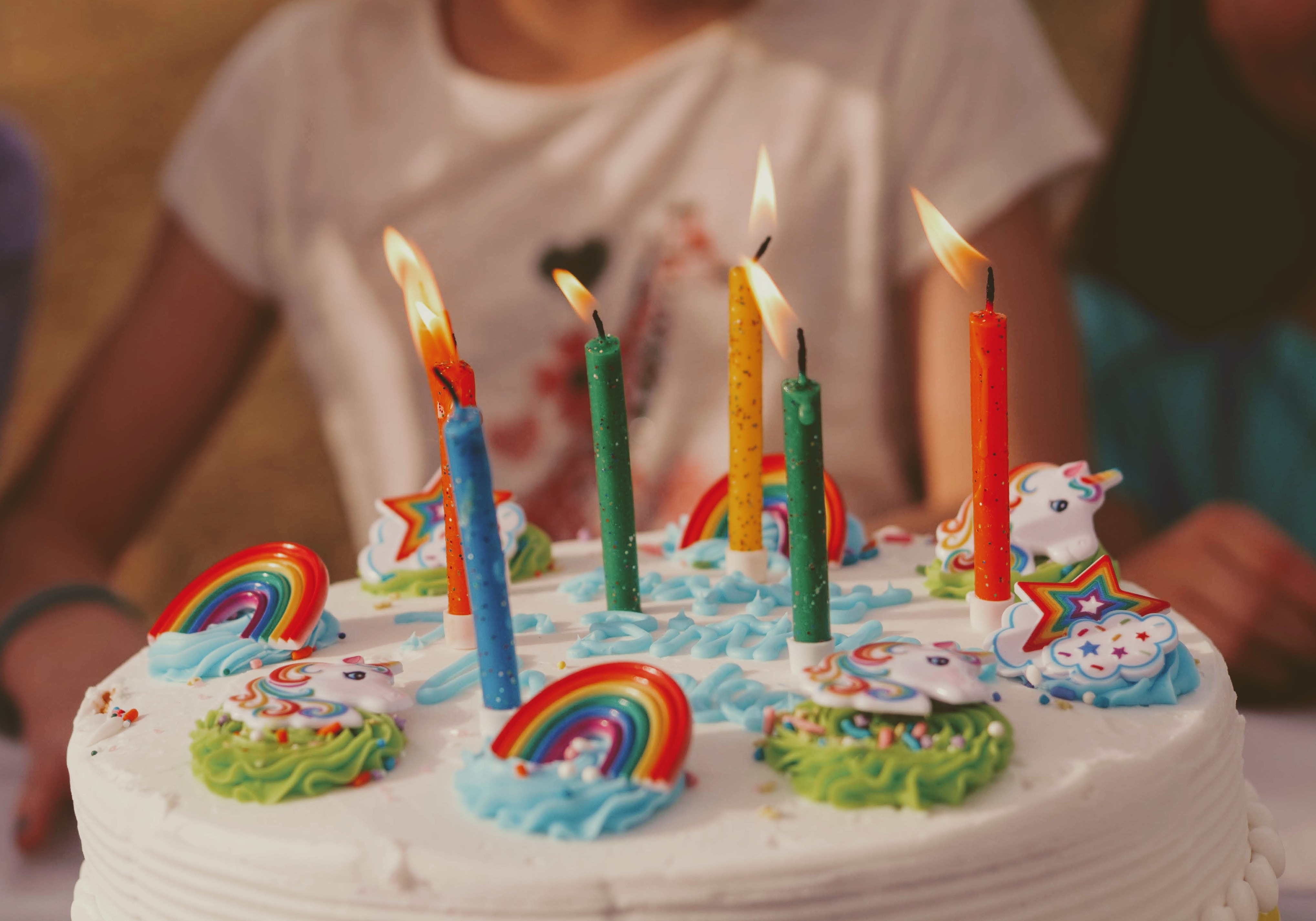photo: birthday cake with candles, sprinkles and decorations help by little girl
