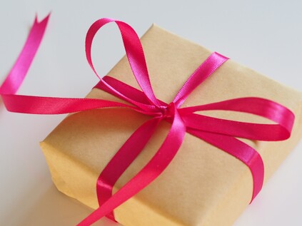 photo of gift box wrapped in brown paper with a pink silk ribbon tied in a bow