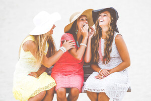 photo: three young women siting on a bench talking and laughing in sunhats