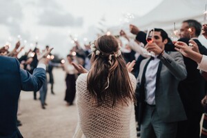 wedding crowd welcomes bride and groom with sparklers