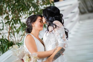 dark-haired brides embracing one another on a staircase