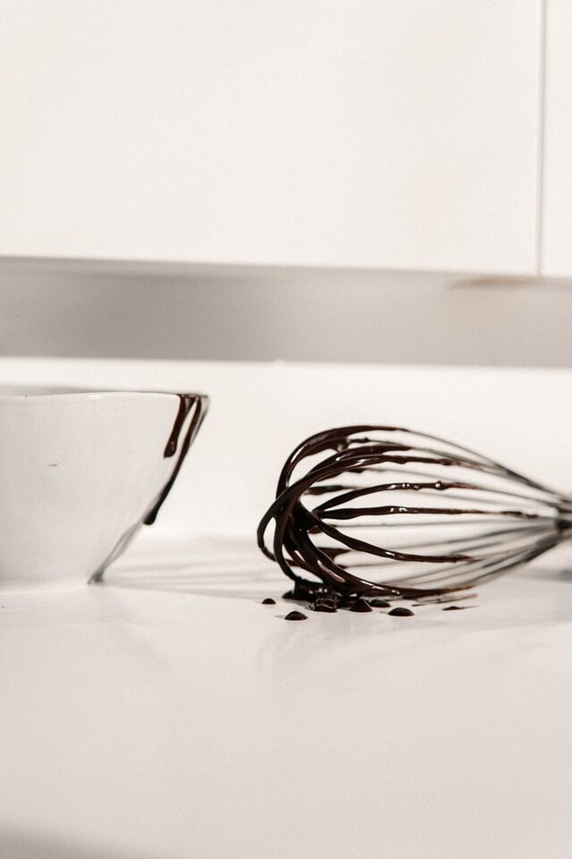 photo, melted chocolate on a wisk and the edge of a bowl