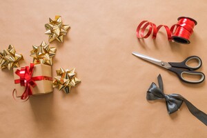 golden bows, red ribbon, and a pair of scissors on top of a light brown background