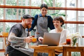 diverse group of friends looking at a computer screen in a cafe