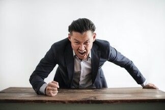 business man completely losing his temper and slamming a desk