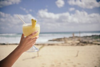 woman holding a non alcoholic beverage in her hand at the beach