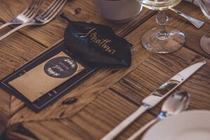 table setting at a wedding with place cards on a wooden table