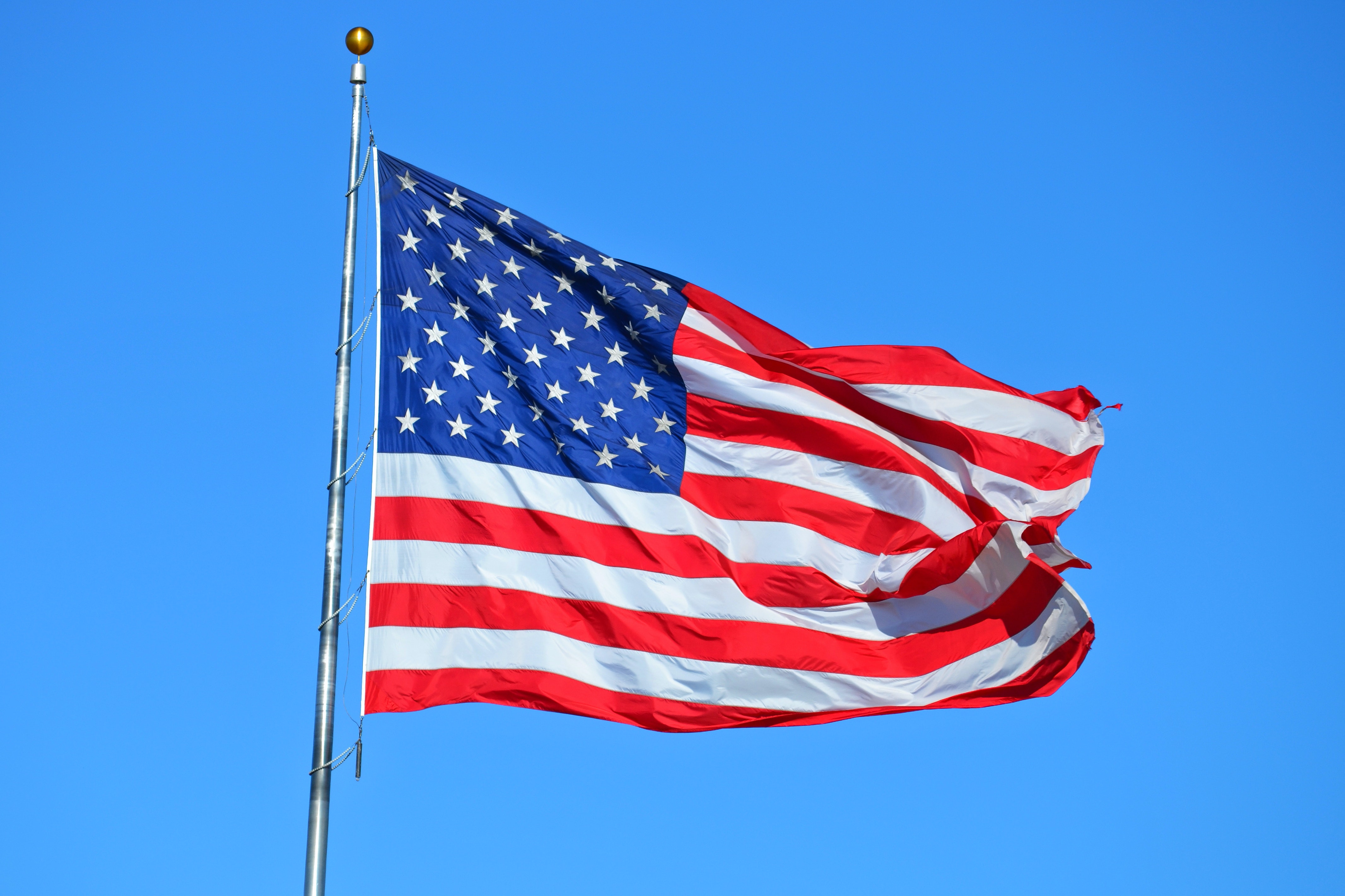 american flag flying in the breeze, with blue sky in the background