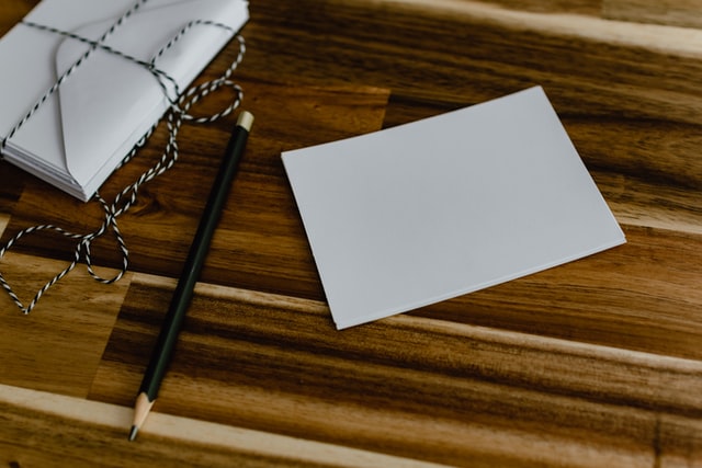 photo: notecard wrapped in string, pencil, and single card sitting on a wood surface