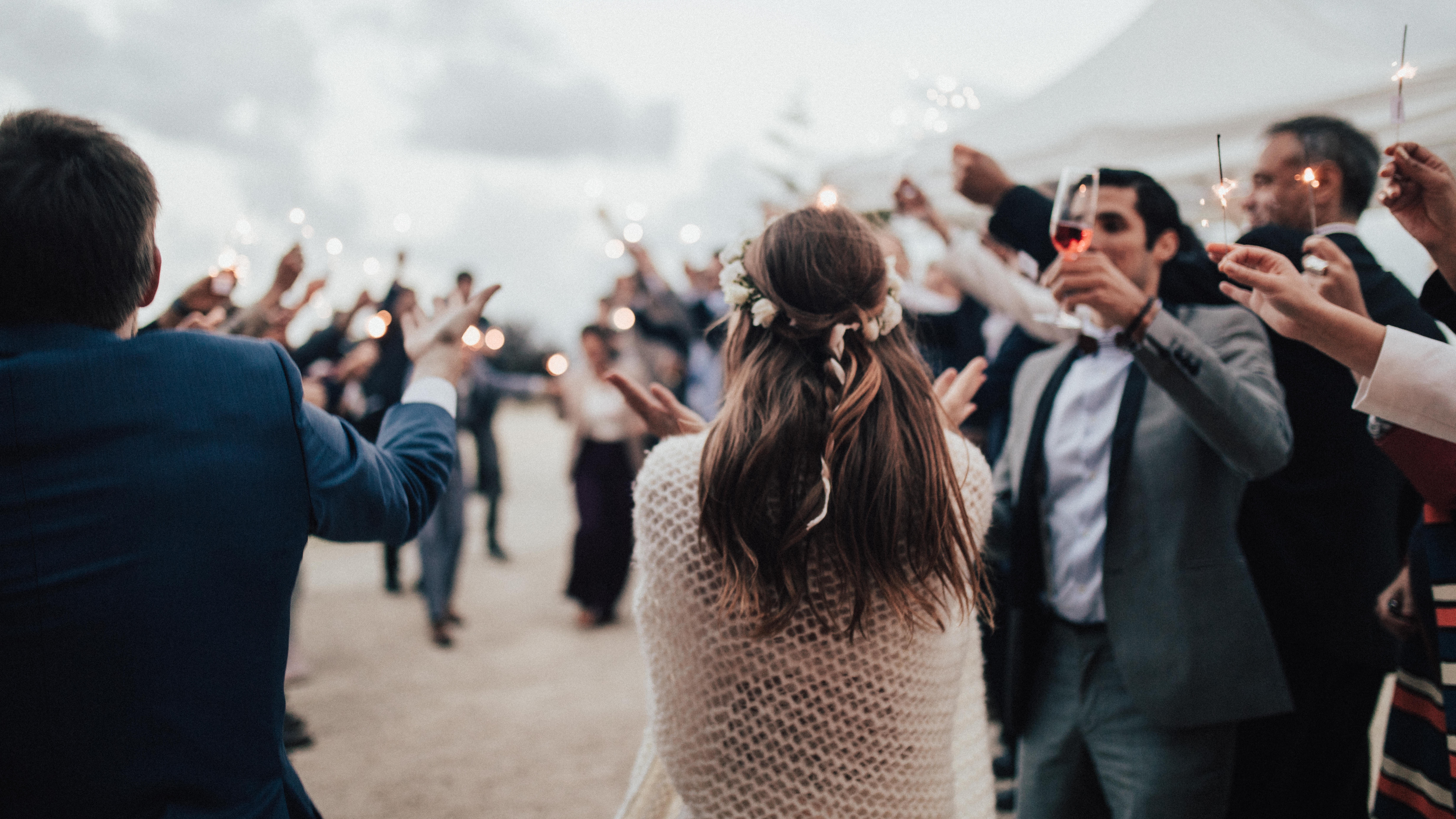 wedding crowd welcomes bride and groom with sparklers