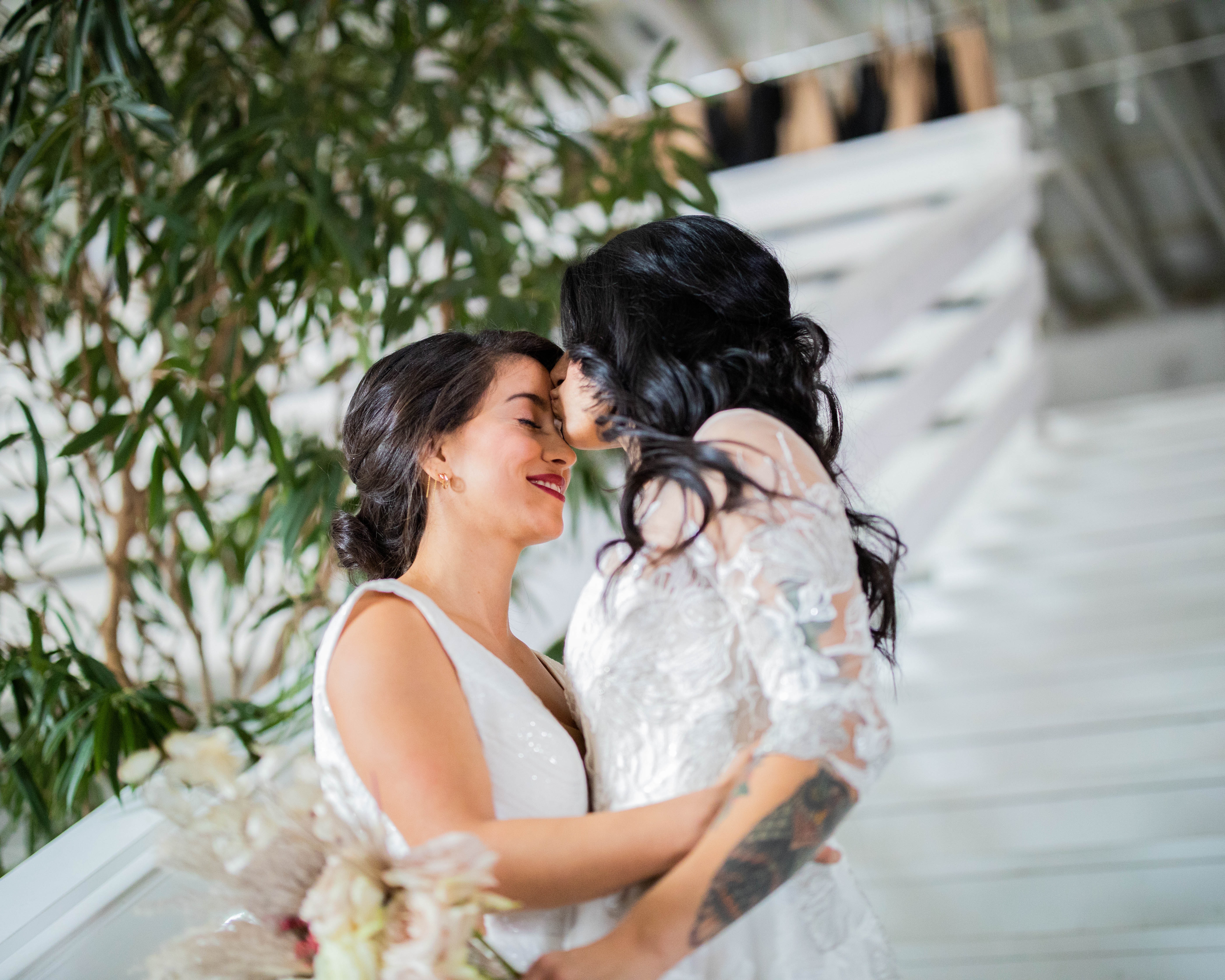 dark-haired brides embracing one another on a staircase