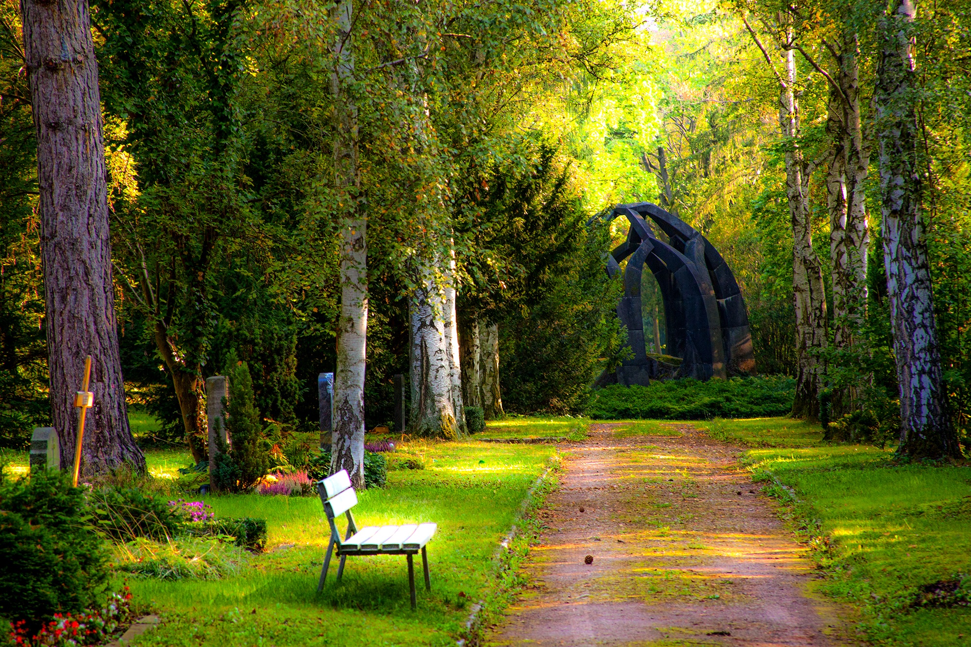 lush green cemetary with a bench and tombstones