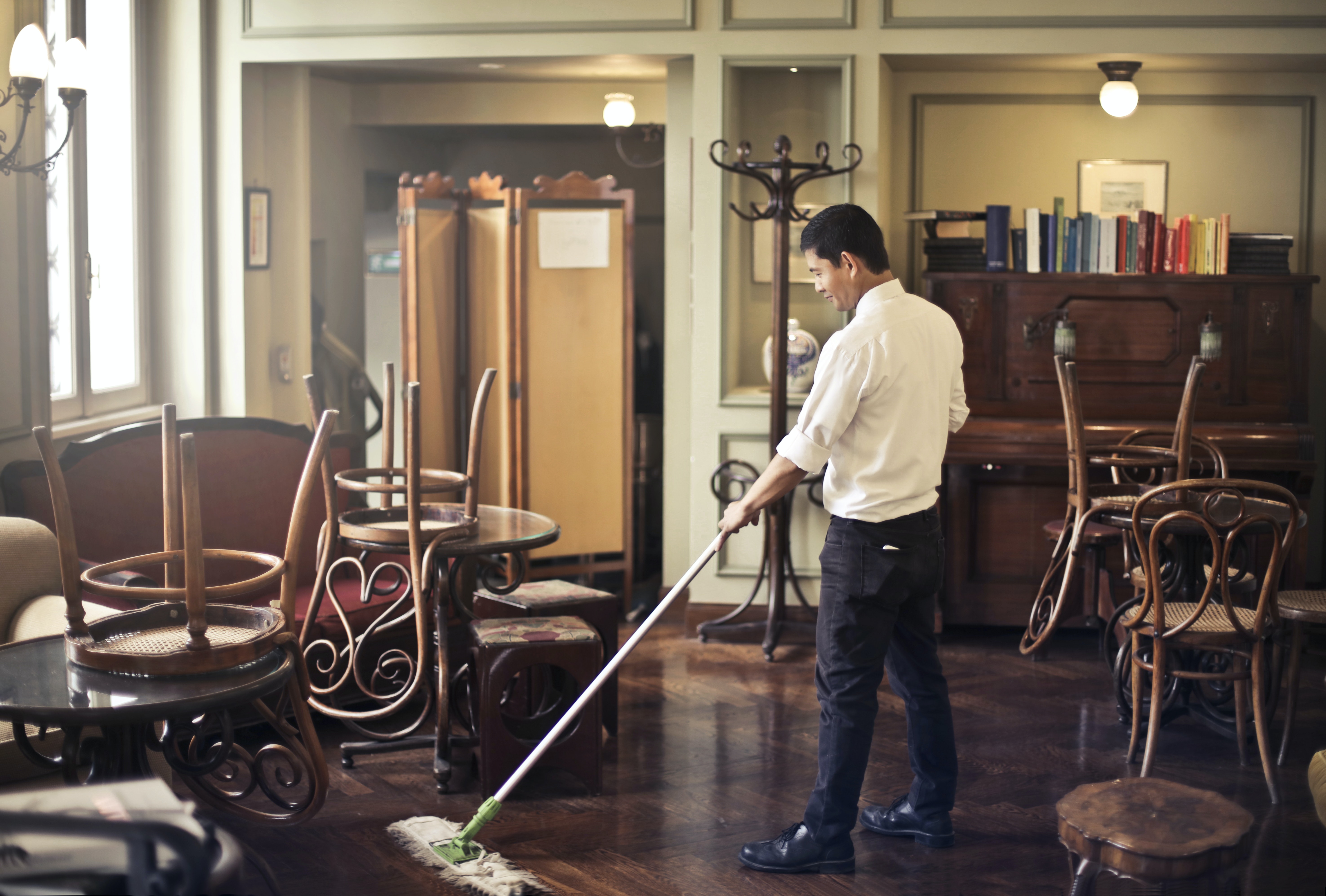 professional cleaner mopping a wooden floor in a retro-looking parlor