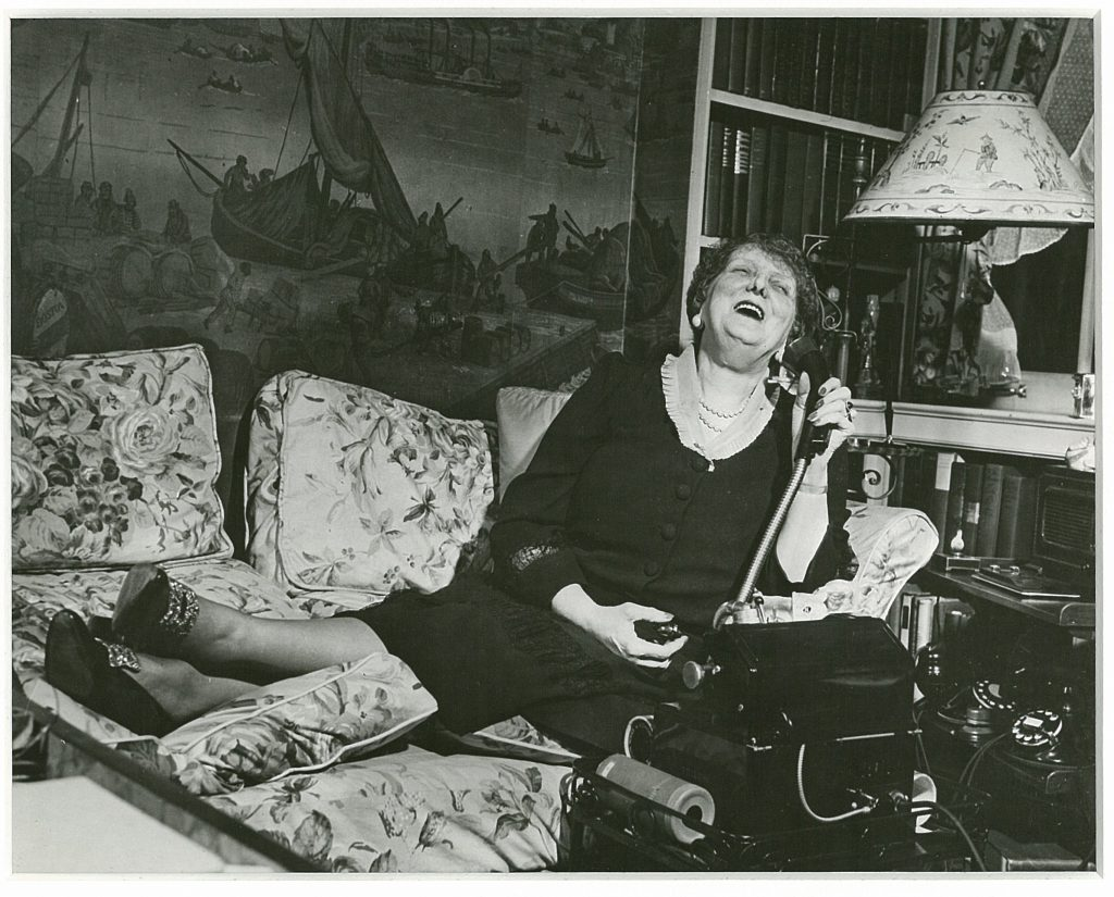 photo: Emily Post reclining on a daybed laughing while talking on the phone