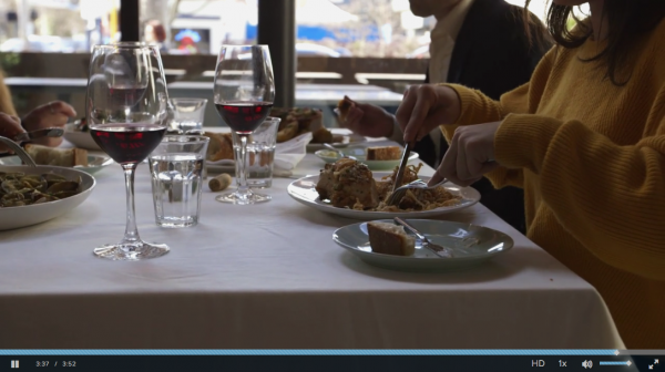 photo: several diners at a table cut into a main course with knives and forks