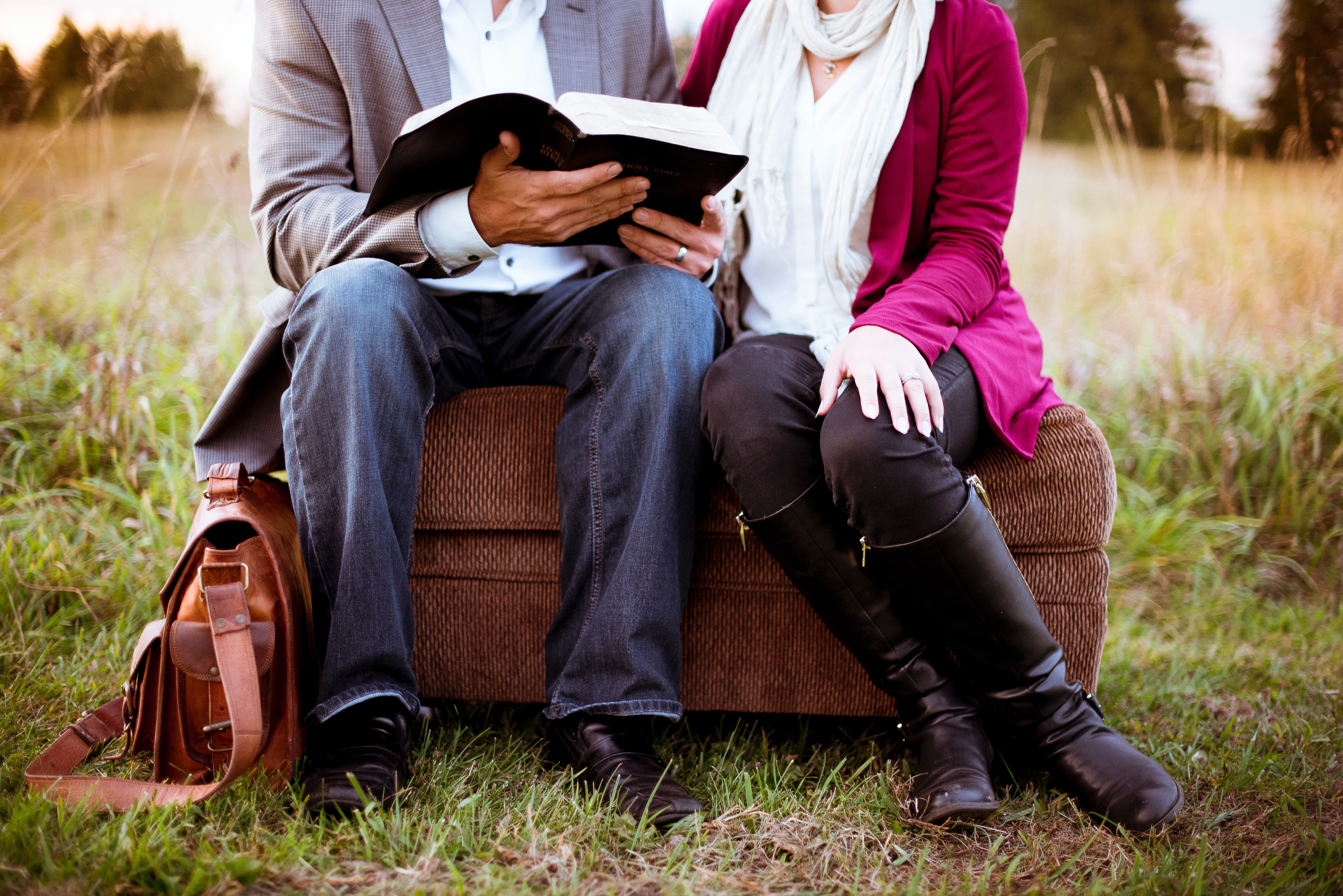 husband and wife reading the bible on an ottoman together