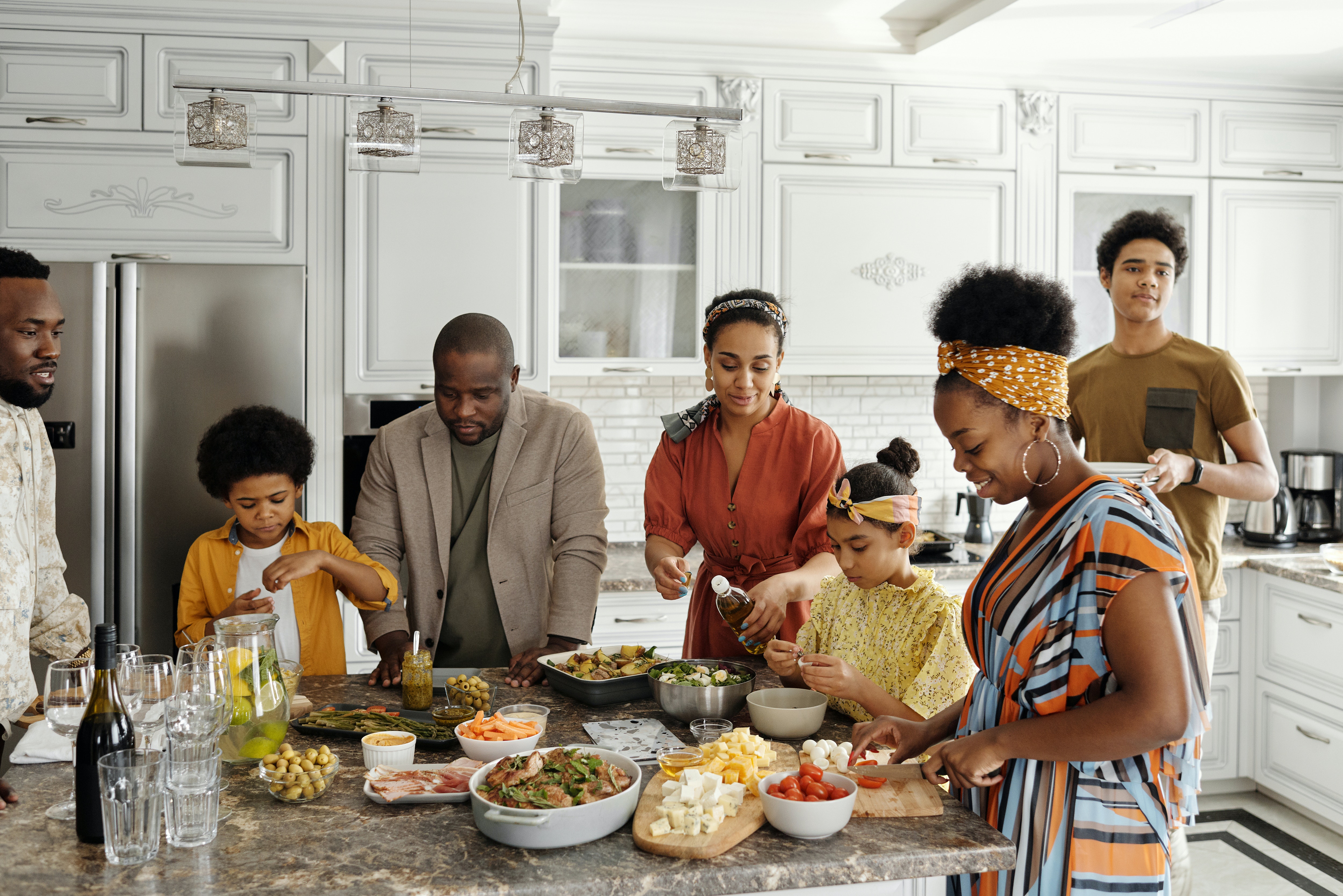 big family gathered around a countertop with an array of delicious-looking food spread out in front of them